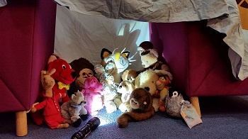 Photo of a group of stuffed animals sitting around a camp lantern