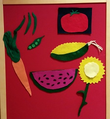Photo of a red felt board with pieces of felt made to look like fruits and vegetables and flowers