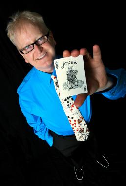 Magician in blue shirt holding up a pack of cards