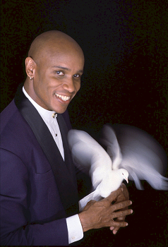 Smiling magician in a tuxedo holding a white dove