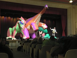 Photo of three giant inflatable dinosaurs and a man on a stage