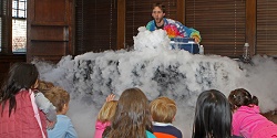 Photo of a man in a tie-dyed shirt standing behind a table that has steam flowing out over it