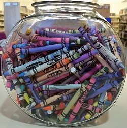 Photo of a glass fishbowl filled with crayons