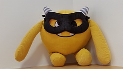 Photo of a yellow stuffed animal monster wearing a black eye mask
