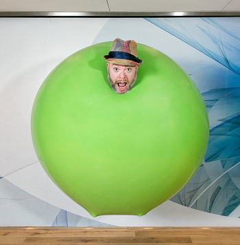 Photo of a man's head coming out of a giant green balloon