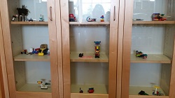 Photos of lego models made by children on display in a glass case