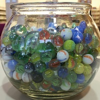 Photo of a glass bowl full of multicolored marbles