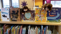 Photo of two monkey puppets looking a new library picturebooks