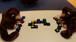 Photo of two monkey puppets playing a game with multicolored tiles
