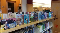 Photo of new library books lined up for display on top of a library bookshelf