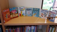 Photo of seven new library books on display on top of a library shelf