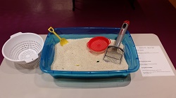 Photo of a plastic tub filled with rice and tools to scoop and play with the rice