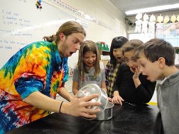 Photo of a teacher showing four children an exciting science experiment