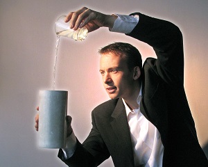 Photo of a man dressed as a magician pouring something from one container to another