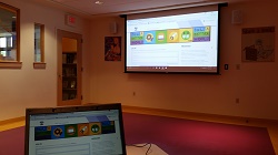 Photo of a computer laptop screen in front of a large video screen