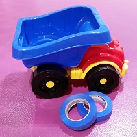Photo of a child's plastic dump truck and two rolls of blue painter's tape