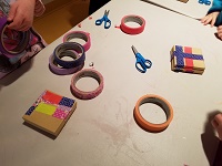 Photo of a plastic table with rolls of colored tape and small cardboard jewelry boxes
