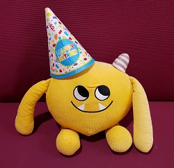 Photo of a yellow stuffed animal monster wearing a birthday hat