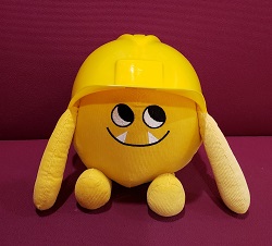 Photo of a yellow stuffed animal monster wearing a construction hat