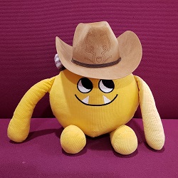 Photo of a yellow stuffed animal monster wearing a cowboy hat