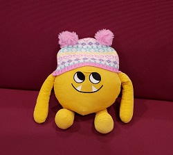 Photo of a yellow stuffed animal monster wearing a winter hat