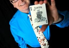 Magician in blue shirt holding up a pack of cards