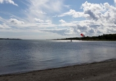 Beach sky with paraglider Photo of the seashore looking out to a person paragliding on the ocean
