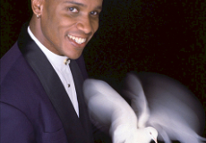 Smiling magician in a tuxedo holding a white dove