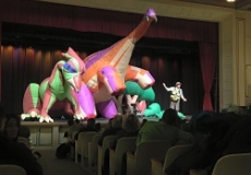 Inflatable Dinosaurs Photo of three large inflatable dinosaurs and a man on a stage