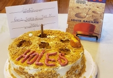 Photo of a cake with the word holes on it and the book Holes by Louis Sachar