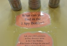 Photo of three plastic bottles on a table and a sign that says what can you find in the i spy bottles