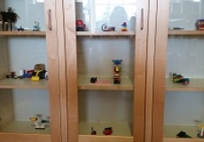 Photos of lego models made by children on display in a glass case