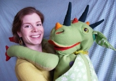 Photo of a woman with a large green dragon puppet