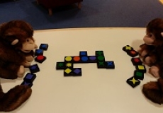 Photo of two monkey puppets playing a game with multicolored tiles