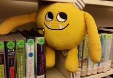 Nibbles and the books on CD Photo of a yellow stuffed animal monster on a shelf with library audiobooks