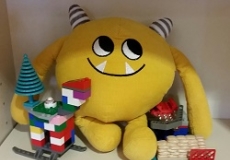 Photo of a yellow stuffed animal monster with legos