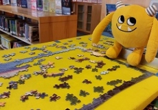 Nibbles and the Puzzle Photo of a yellow stuffed animal monster sitting by a jigsaw puzzle