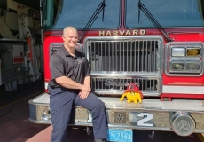 Yellow stuffed animal monster on a fire truck with fire chief
