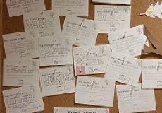 Photo of a bulletin board with many postcards pinned to it