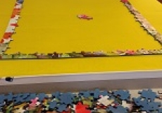 Photo of a partially assembled jigsaw puzzle on a yellow piece of felt