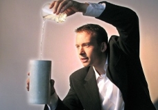 Photo of a man dressed as a magician pouring something from one container to another