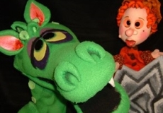 Photo of a green dragon puppet and a prince puppet