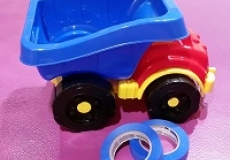 Photo of a child's plastic dump truck and two rolls of blue painter's tape