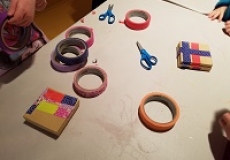Photo of a plastic table with rolls of colored tape and small cardboard jewelry boxes